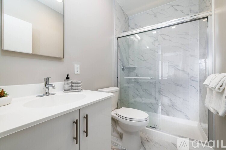 A white bathroom with a marble shower and toilet.