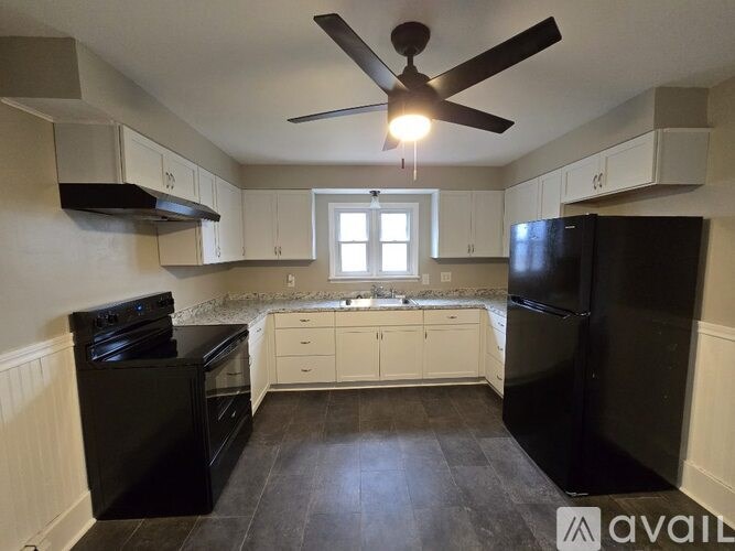 A kitchen with black appliances and white cabinets.