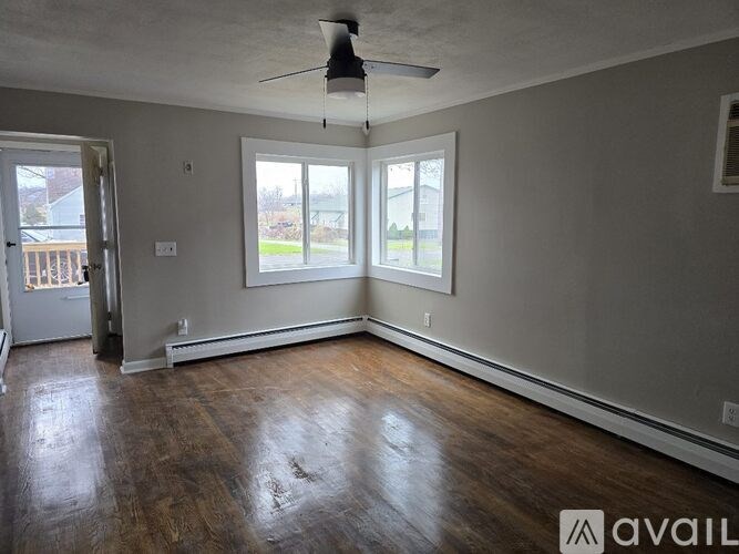A room with a ceiling fan and two windows.