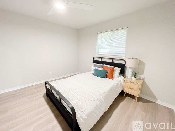 A bedroom with a bed, nightstand, and a window with blinds.