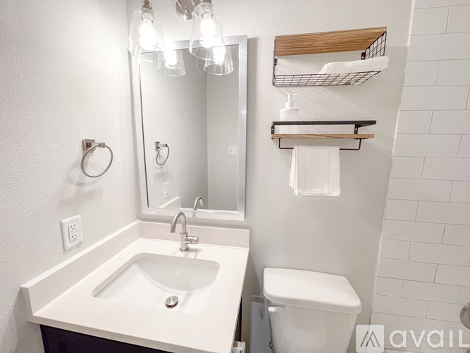 A white bathroom with a sink, toilet, and mirror.