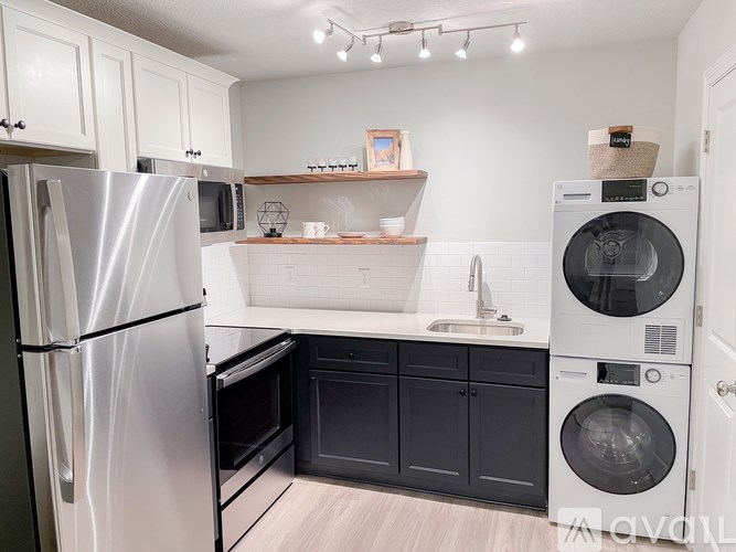 A modern kitchen with a stainless steel refrigerator, black cabinets, and white countertops.