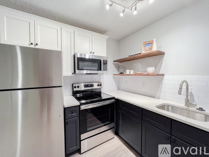 A modern kitchen with a stainless steel refrigerator, black cabinets, and a white countertop.