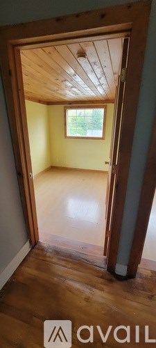 A room with wooden floors and a window is available for rent.