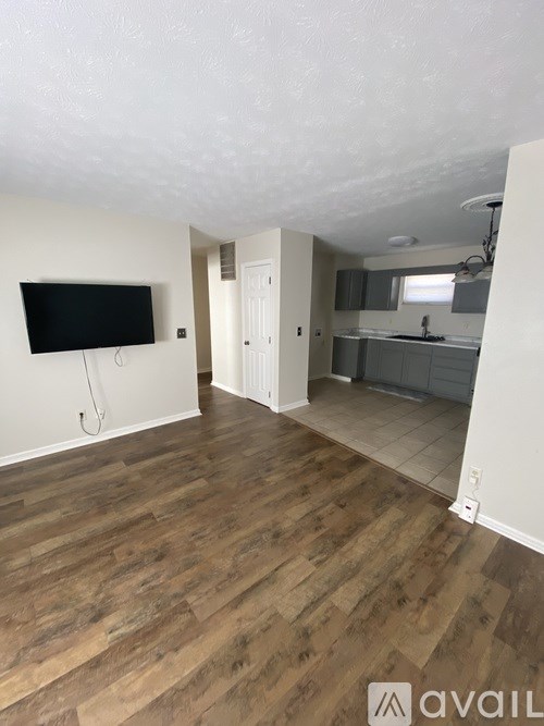 A room with a wooden floor and a flat screen TV mounted on the wall.