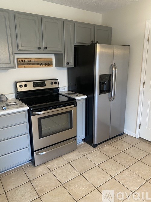A kitchen with a black fridge and stove top oven.