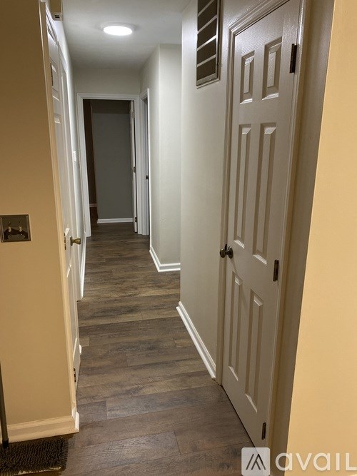 A hallway with a white door and a wooden floor.