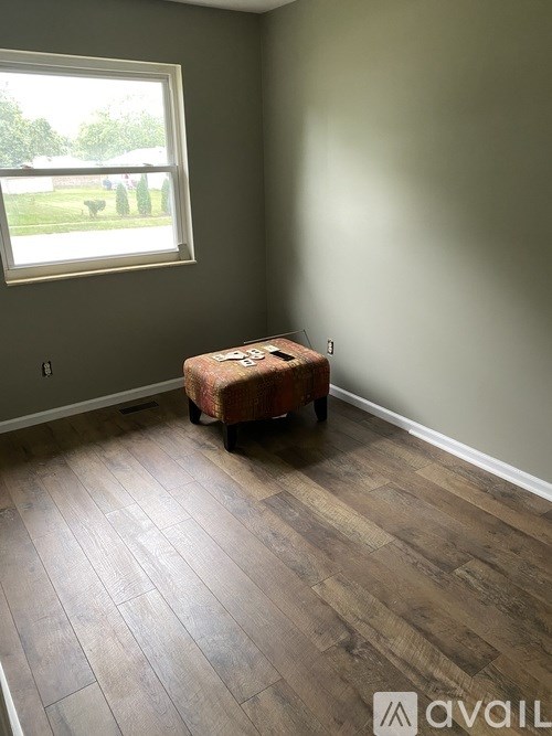 A room with a window and a wooden floor.