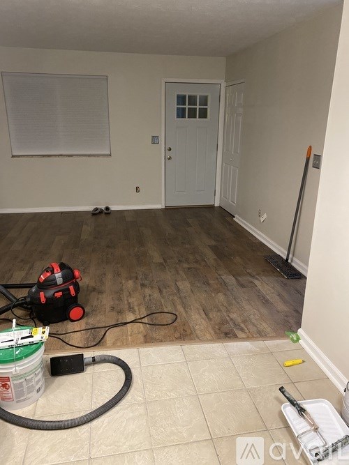A room with a white door and a vacuum cleaner on the floor.
