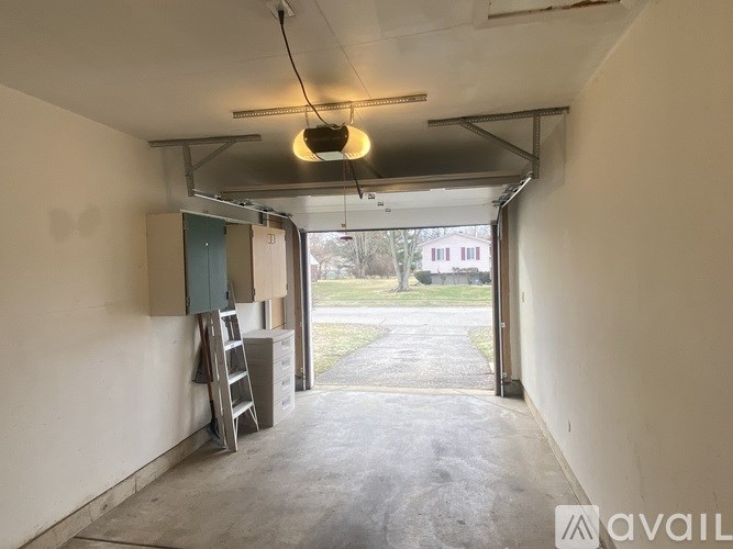 A garage with a ladder and a hanging light fixture.
