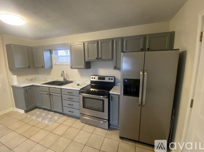 A kitchen with a refrigerator, oven, and sink.