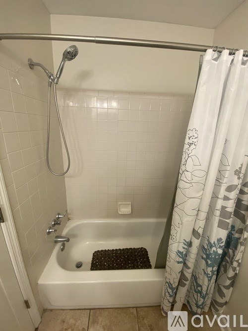 A white bathtub with a shower head and a shower curtain.