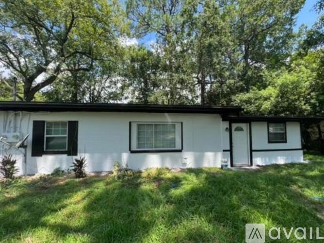 A white house with a black roof and a green lawn in front.