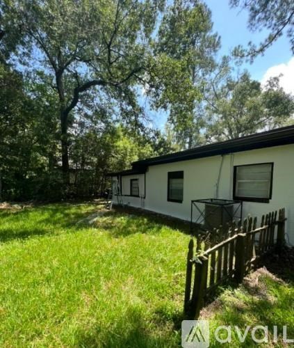 A white mobile home with a wooden fence in front of it.