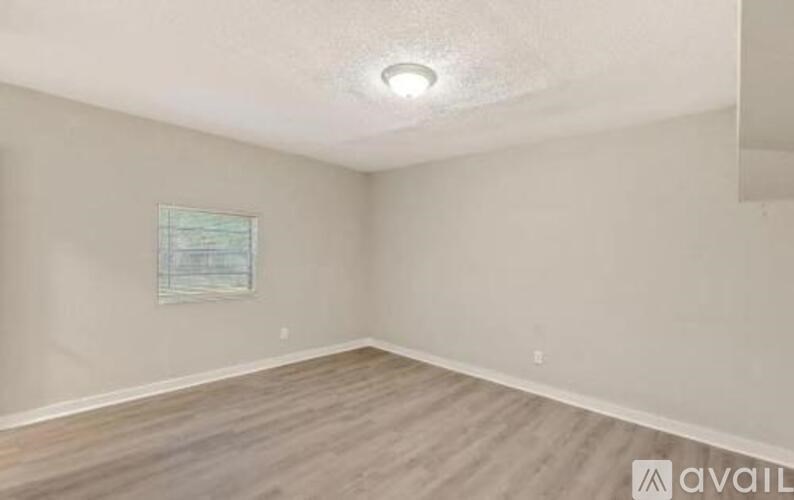 A room with wooden flooring and a window with blinds.