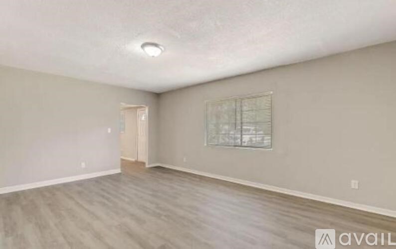 A room with a wooden floor and a window with blinds.