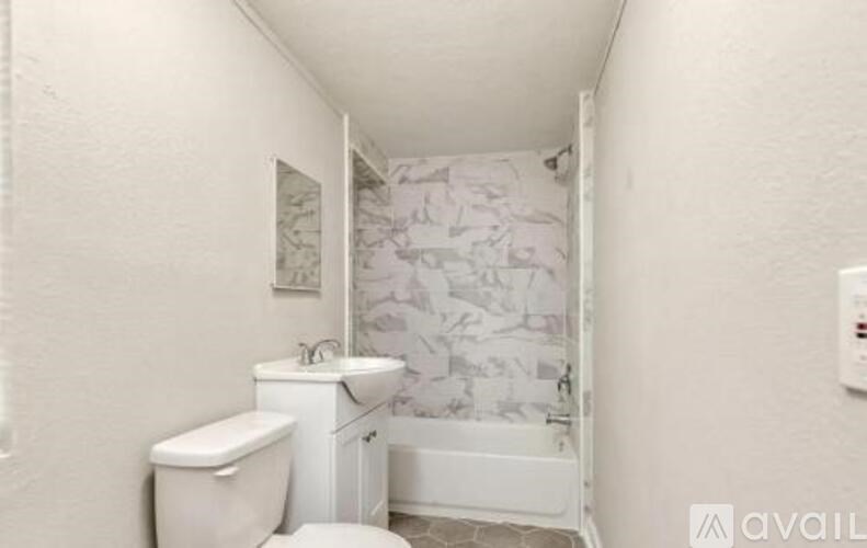 A white toilet sits next to a white sink in a small bathroom.