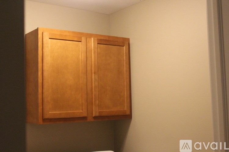 A wooden cabinet with two doors is mounted on a wall.