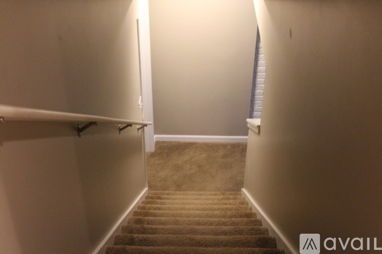 A staircase with a carpeted runner and a wall on the left side.