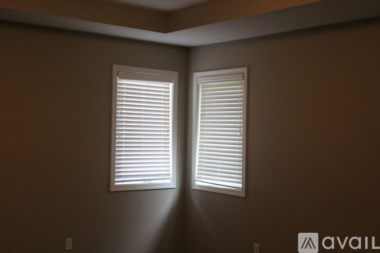 A room with two windows covered in white blinds.