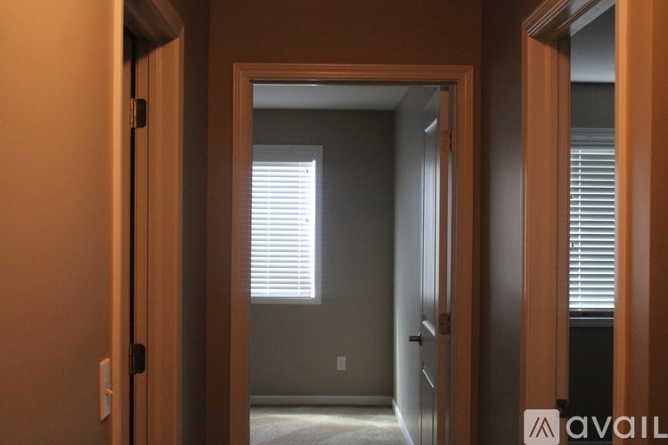A hallway with a door on the left and a window with blinds on the right.