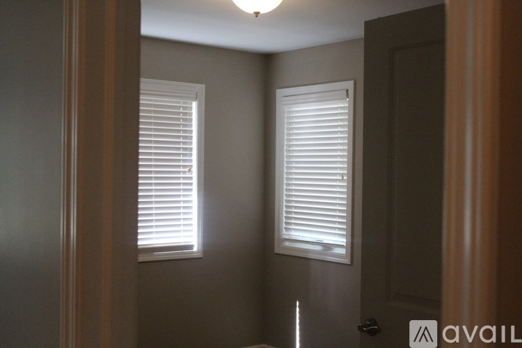 A room with a door and two windows with blinds.