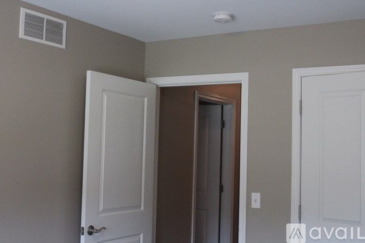 A room with a white door, a brown door, and a white wall.