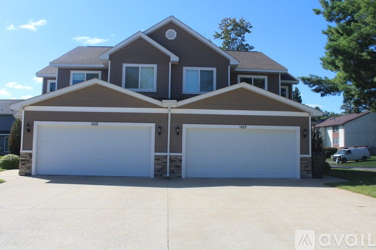 A house with a brown roof and two white garage doors.