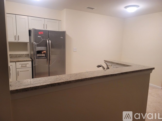 A kitchen with a refrigerator, sink, and cabinets.