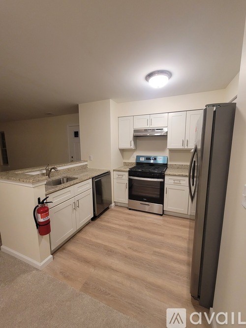 A kitchen with a black fridge and a fire extinguisher on the wall.