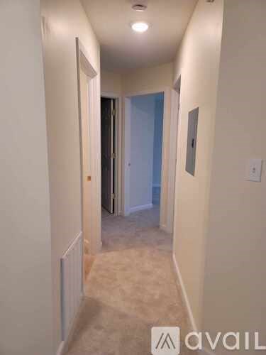 A hallway with a carpeted floor and white walls.