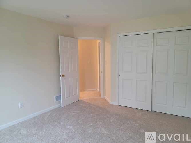 A room with a carpeted floor and two white doors.