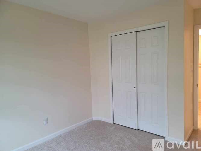 A room with a white door and carpeted floor.
