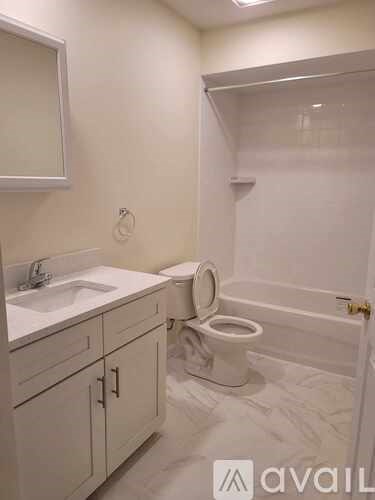 A white bathroom with a toilet, sink, and mirror.