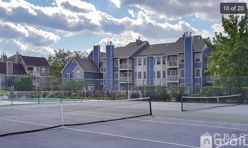 A tennis court is in front of a large building.