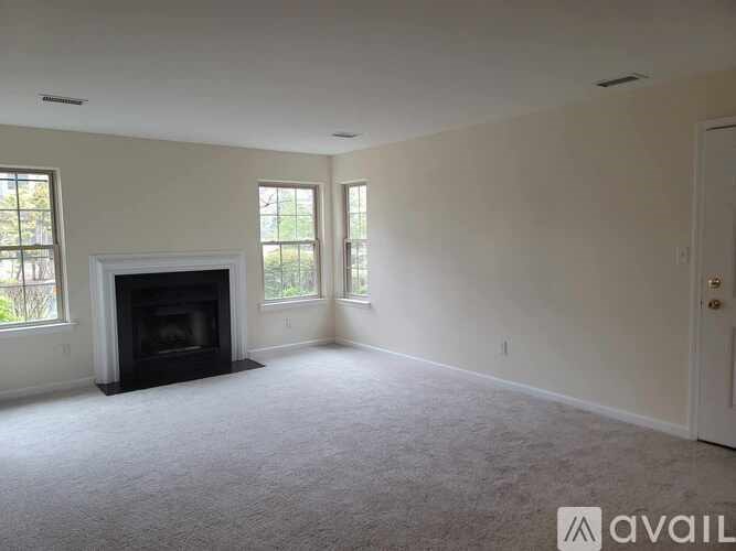 A living room with a fireplace and carpeted floor.