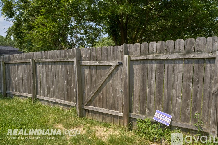 A wooden fence with a sign that says "For Sale" in front of it.