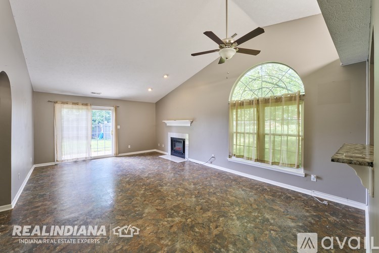 A spacious room with a fireplace and a ceiling fan.