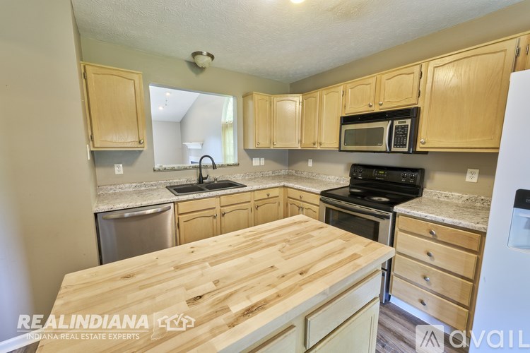 A kitchen with wooden cabinets and a wooden counter top.