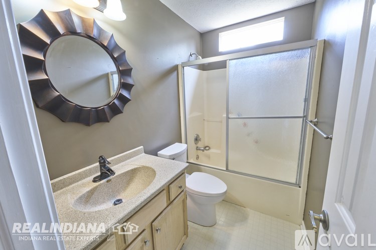 A bathroom with a round mirror and a sink with a black faucet.