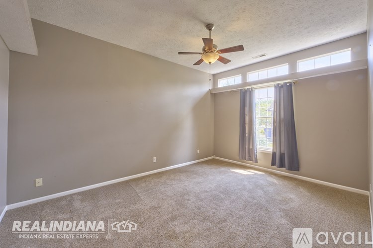 A spacious room with a ceiling fan and carpeted floor.