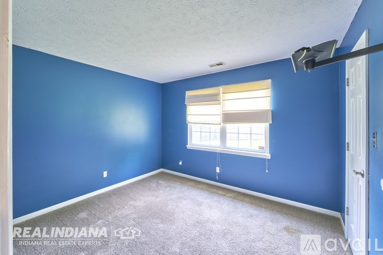 A room with blue walls and a window with blinds.