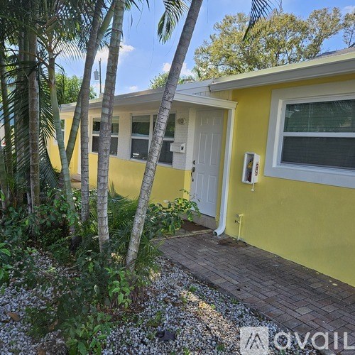A yellow house with a white door and a small garden in front.