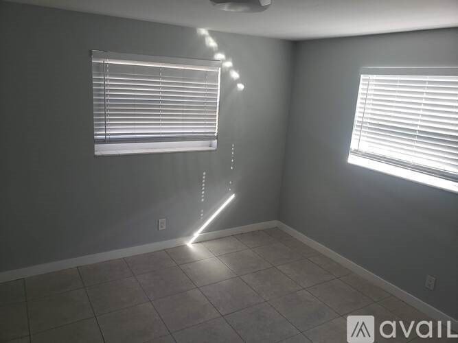A room with a grey wall and a window with blinds.