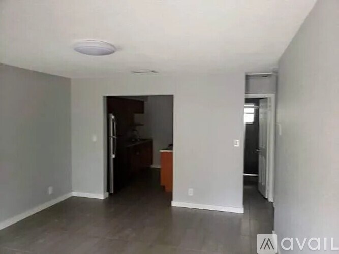 A room with a refrigerator and a wooden cabinet.