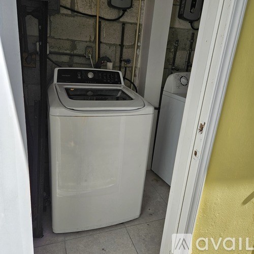 A white washing machine sits in a small laundry room.