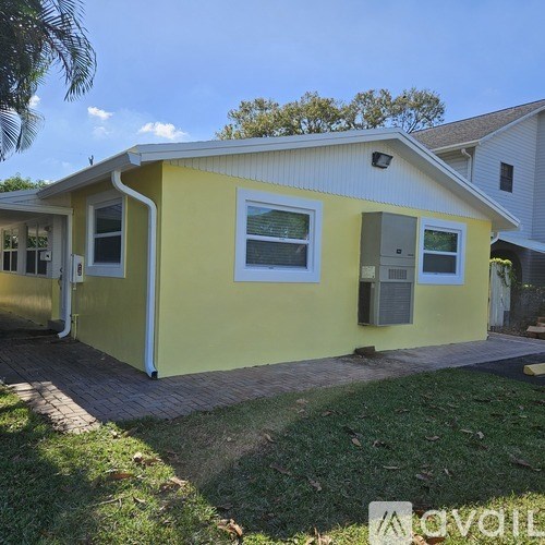 A yellow house with a white roof and a grey door.