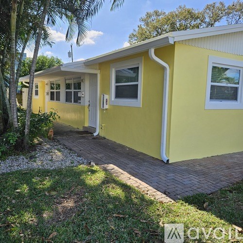 A yellow house with a white door and windows.
