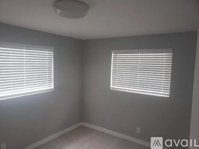 A room with two windows covered in white blinds.