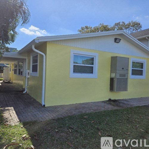 A yellow house with a white roof and a brick walkway in front.